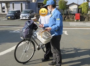学生に自転車のヘルメット着用を促すパンフレットを配布する状況